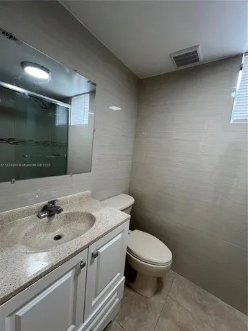 a bathroom with a granite countertop sink a toilet and a mirror