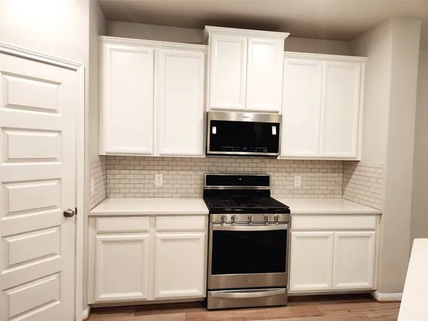 a kitchen with white cabinets and a stove top oven