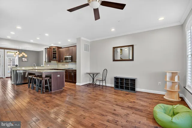 a living room with stainless steel appliances kitchen island granite countertop a table chairs and a refrigerator