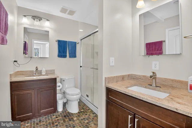 a bathroom with a granite countertop sink a toilet and a mirror