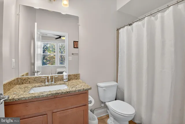 a bathroom with a granite countertop sink toilet and a mirror