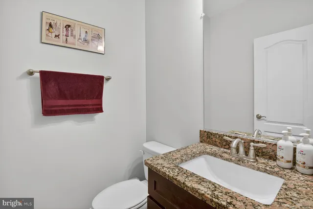 a bathroom with a granite countertop toilet sink and mirror