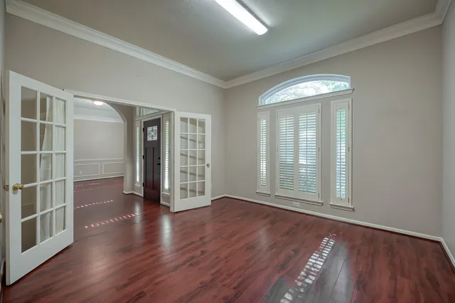 an empty room with wooden floor and windows