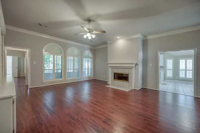 a view of an empty room with wooden floor and a fireplace