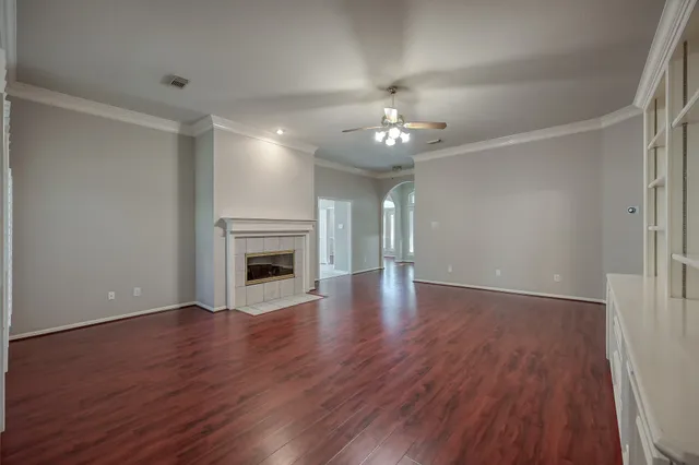 a view of an empty room with wooden floor and fireplace
