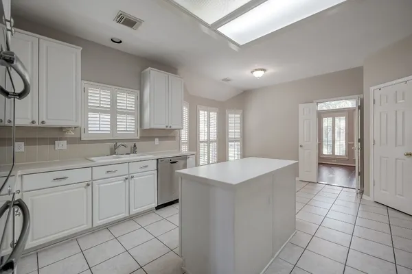 a large white kitchen with a sink window and cabinets