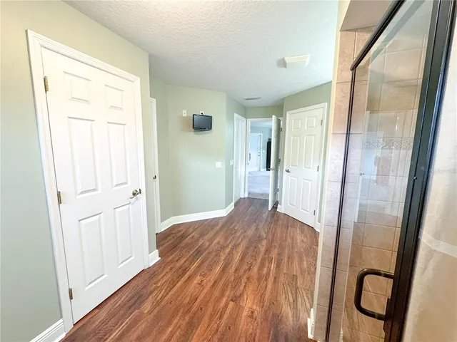 a view of a hallway to a livingroom with wooden floor and a cabinet
