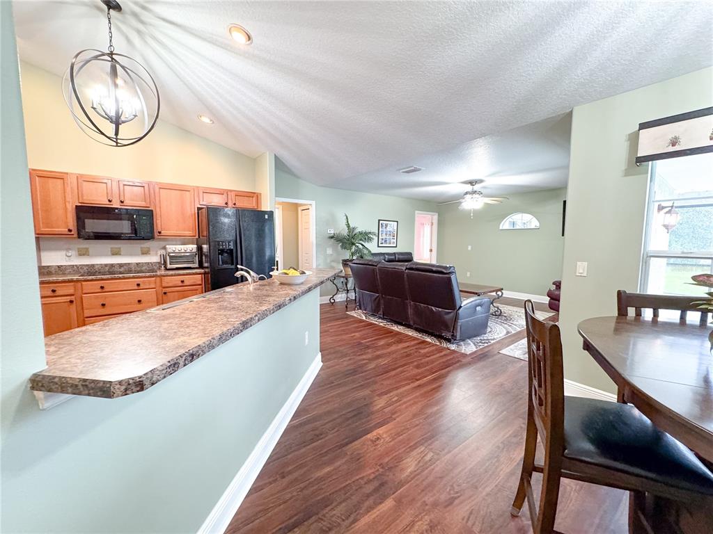 6282 Northeast 61st Ave Road Silver Springs, FL 34488 - Photo 27 of 73 a large kitchen with stainless steel appliances granite countertop a stove a sink dishwasher a dining table and chair with wooden floor