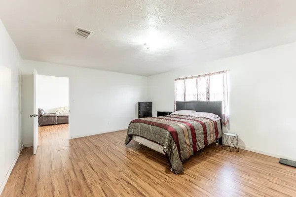 a spacious bedroom with a bed and wooden floor