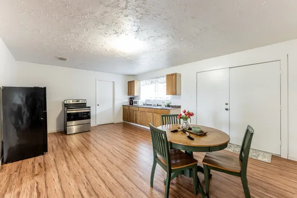 a kitchen with a dining table chairs and refrigerator
