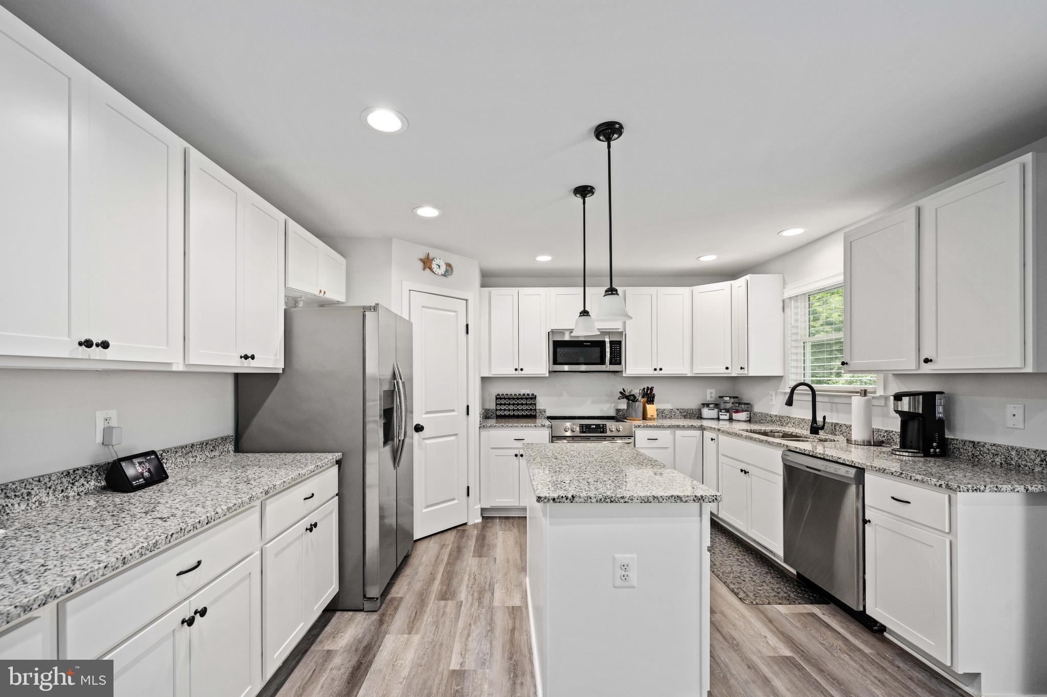 133 7th Street Colonial Beach, VA 22443 - Photo 25 of 72 a kitchen with stainless steel appliances granite countertop a refrigerator sink and white cabinets