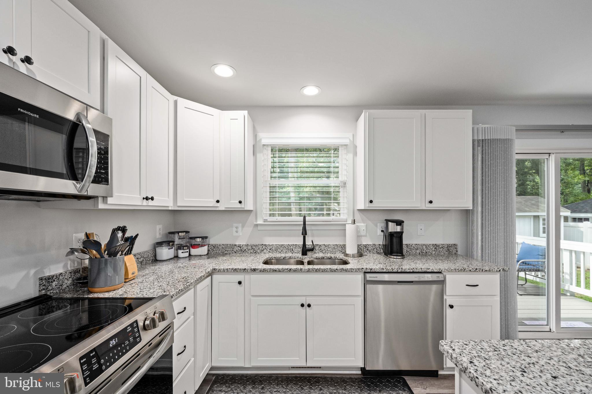 133 7th Street Colonial Beach, VA 22443 - Photo 27 of 72 a kitchen with granite countertop white cabinets sink and stainless steel appliances