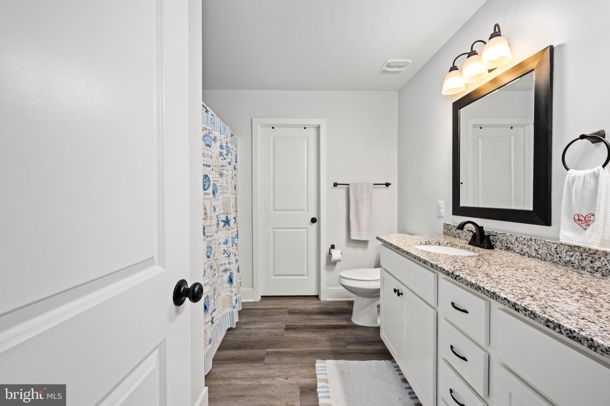 133 7th Street Colonial Beach, VA 22443 - Photo 38 of 72 a spacious bathroom with a granite countertop sink mirror and a toilet