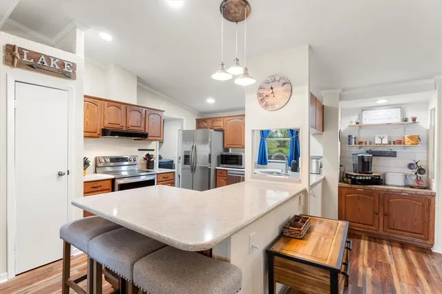 a kitchen with stainless steel appliances granite countertop a stove top oven a refrigerator a sink dishwasher a dining table and chairs with wooden floor