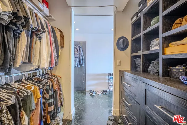 a view of walk in closet with clothes and shoes