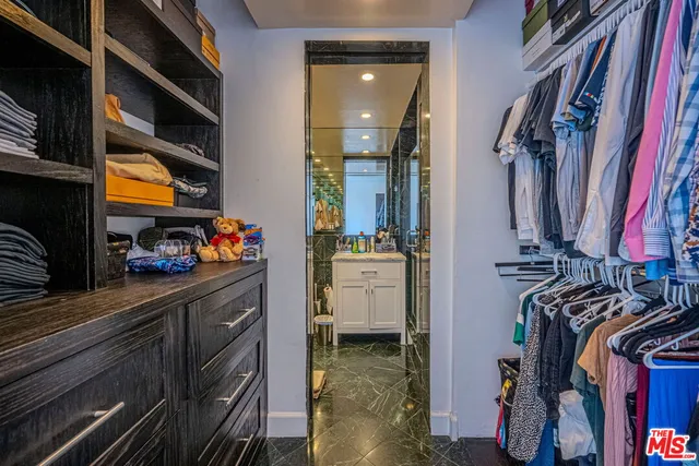 a view of walk in closet with clothes and shoes