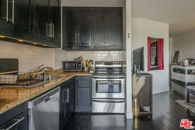 a kitchen with stainless steel appliances granite countertop a sink stove and microwave