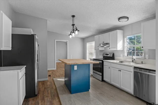 a kitchen with granite countertop a sink stove and refrigerator