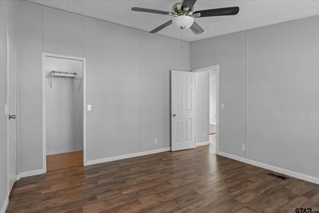 an empty room with wooden floor fan and windows