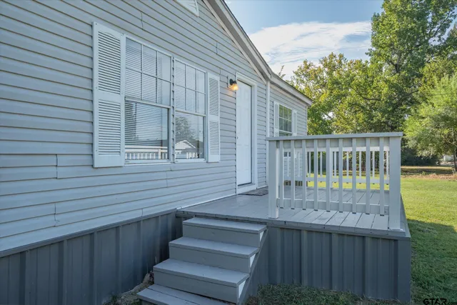 a view of house with wooden deck and furniture
