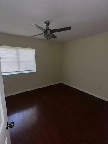 an empty room with wooden floor fan and windows
