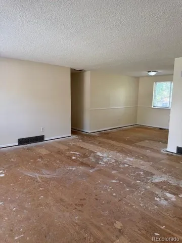 a view of an empty room with window and wooden floor