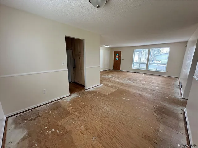 a view of an empty room with window and wooden floor