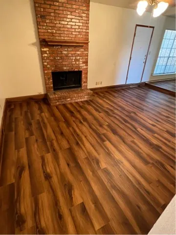 a view of empty room with wooden floor and fireplace