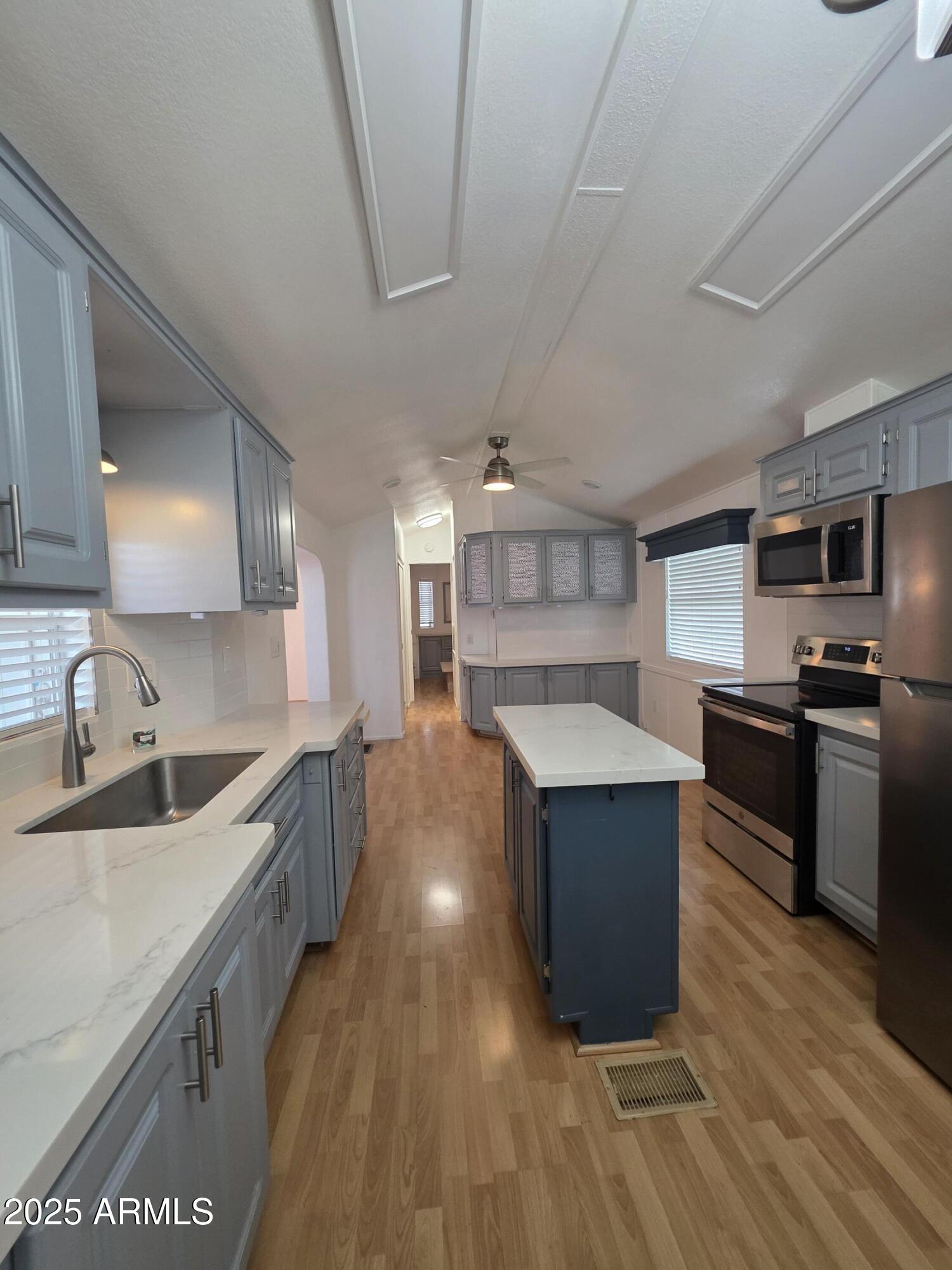 7750 East Broadway Road, Unit LOT 619 Mesa, AZ 85208 - Photo 4 of 33 a kitchen with stainless steel appliances kitchen island granite countertop a sink and a stove top oven