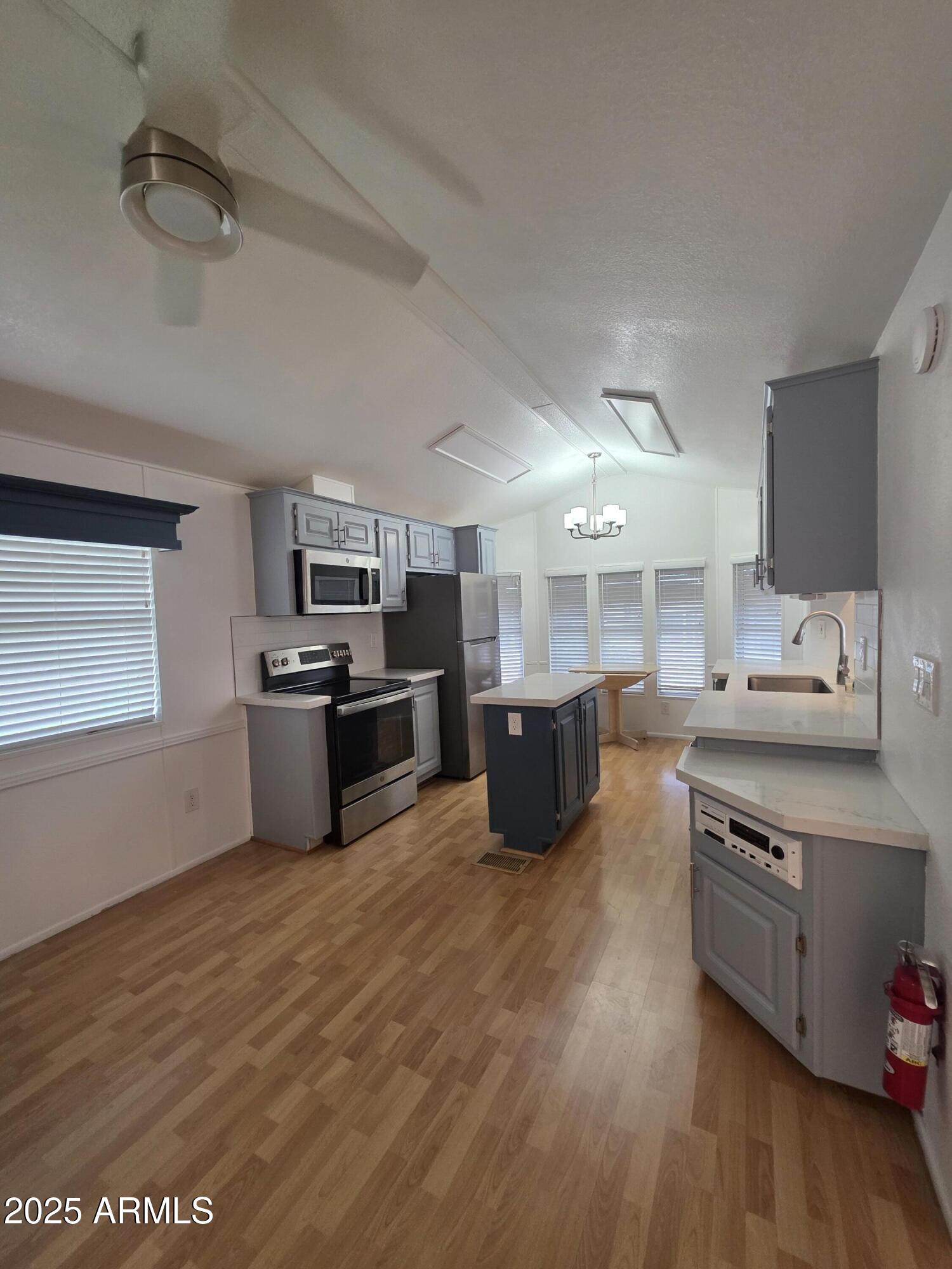 7750 East Broadway Road, Unit LOT 619 Mesa, AZ 85208 - Photo 8 of 33 a large kitchen with stainless steel appliances wooden floors and white cabinets