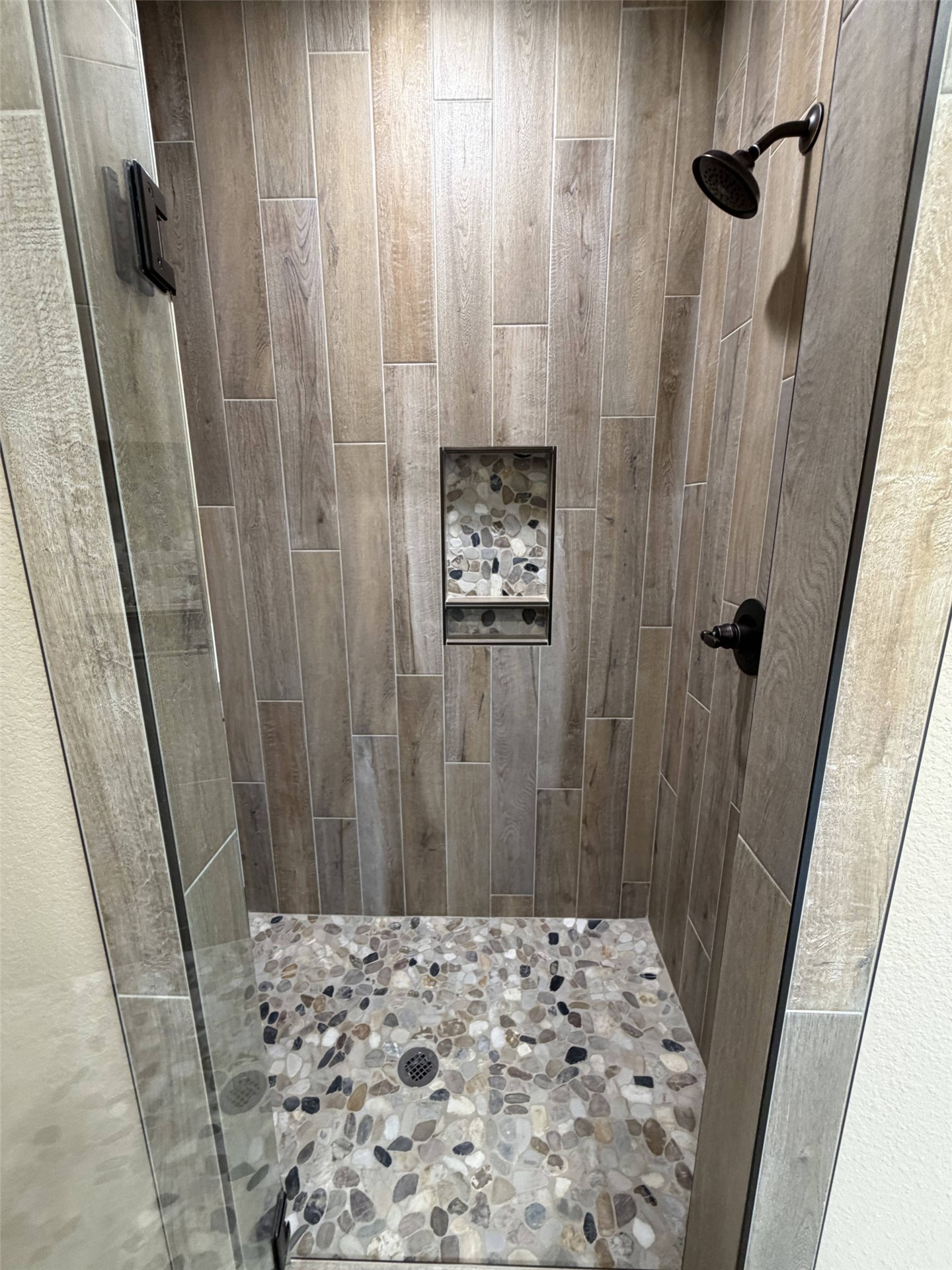 33 Wilderness Road North Calera, OK 74730 - Photo 9 of 39 Walk-in shower with wood-finish vertical tile, pebble-finish floor, and a recessed niche