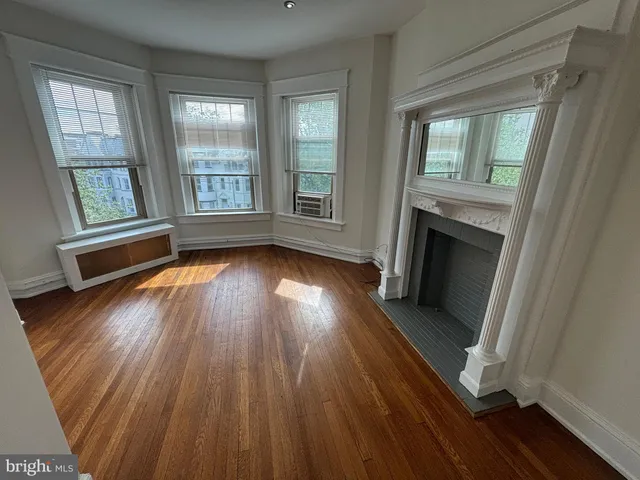 an empty room with wooden floor a fireplace and windows