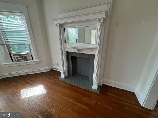 an empty room with wooden floor fireplace and windows
