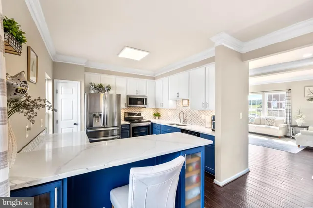 a kitchen with stainless steel appliances a sink a stove a refrigerator cabinets and wooden floor