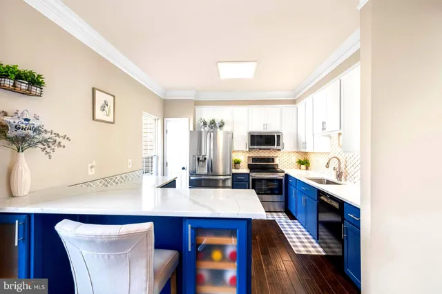 a kitchen with stainless steel appliances a sink a stove a refrigerator cabinets and a dining table