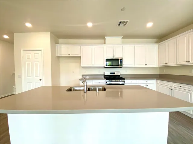 a kitchen with stainless steel appliances granite countertop a sink a stove top oven a counter space and cabinets