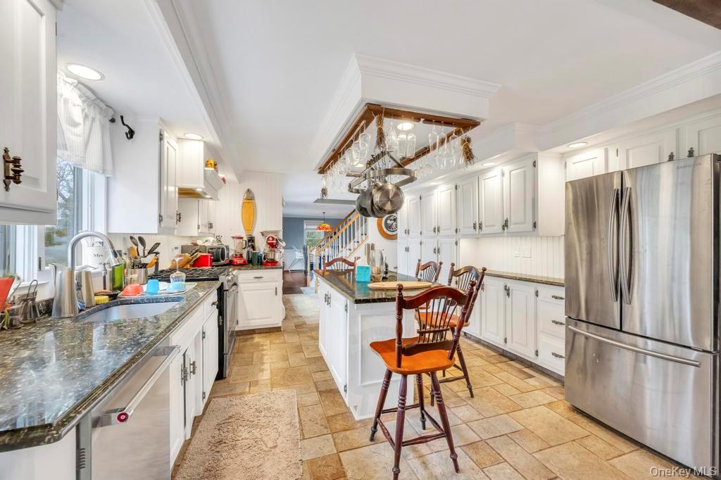 807 Union Avenue Riverhead, NY 11901 - Photo 27 of 43 a kitchen with stainless steel appliances granite countertop a stove top oven a refrigerator a sink dishwasher and white cabinets with wooden floor