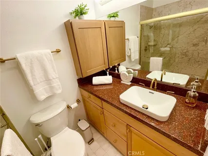 a bathroom with a granite countertop sink toilet and mirror