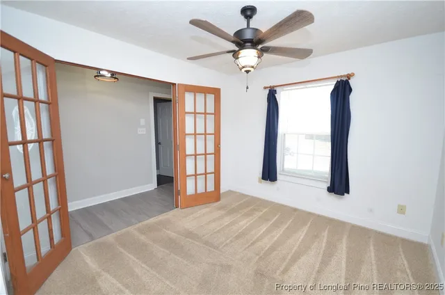 an empty room with windows and fan