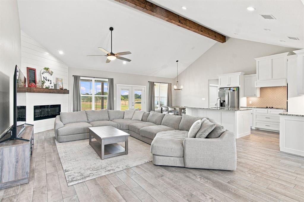 121 Friendship Way Boyd, TX 76023 - Photo 9 of 38 Spacious living area featuring a vaulted ceiling with a rustic wood beam accent and recessed lighting