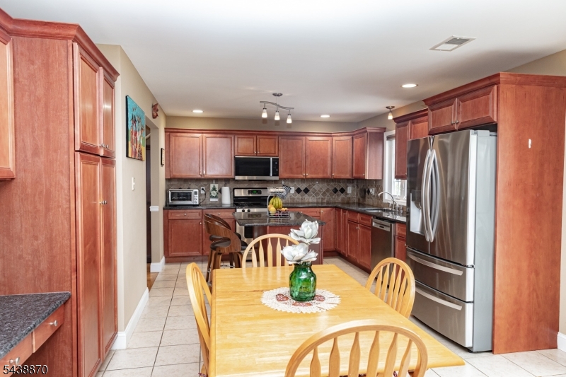 419 Putnam Road Union, NJ 07083 - Photo 14 of 37 a kitchen with stainless steel appliances granite countertop a refrigerator a stove top oven a sink and dining table with wooden floor