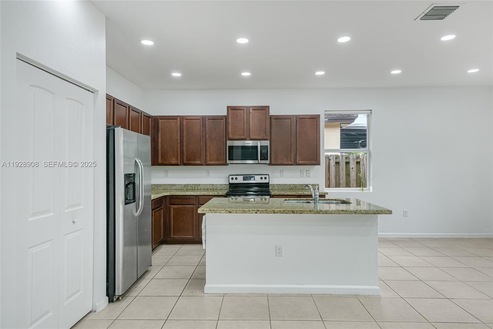 11863 Southwest 253rd Terrace Homestead, FL 33032 - Photo 9 of 30 a kitchen with stainless steel appliances granite countertop a stove top oven a sink and a refrigerator