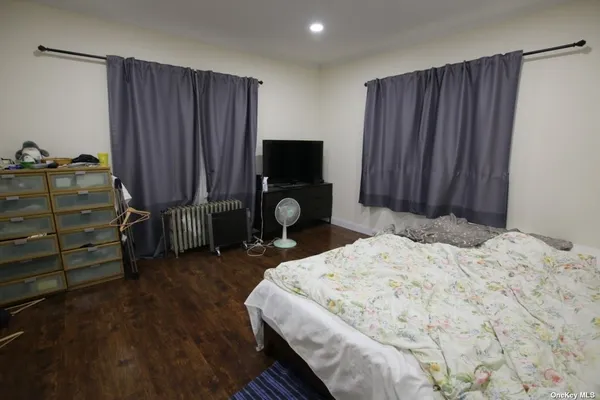 a bed sitting in a spacious bedroom chandelier and a dresser