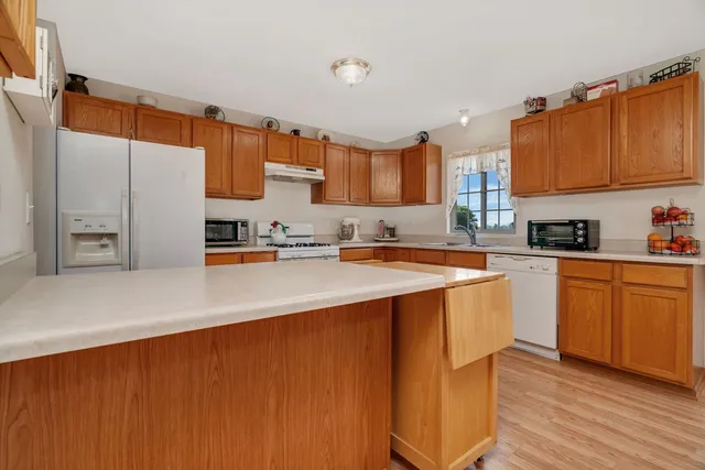 a kitchen with stainless steel appliances a sink dishwasher a stove a refrigerator and cabinets with wooden floor