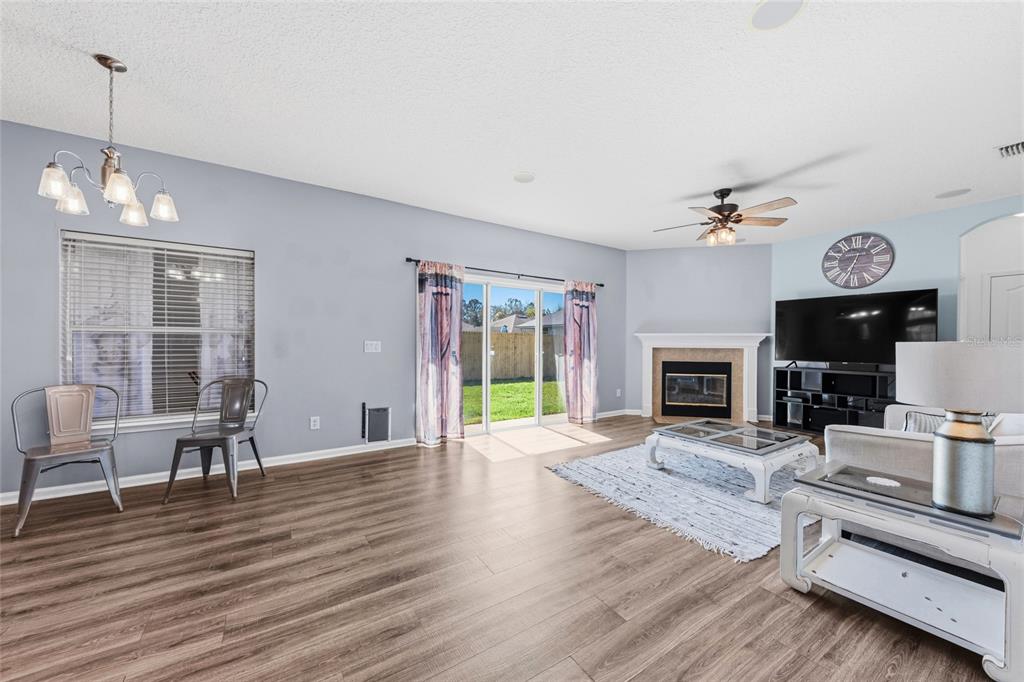 45095 Dutton Way Callahan, FL 32011 - Photo 20 of 36 a view of a livingroom with furniture a fireplace wooden floor and a chandelier
