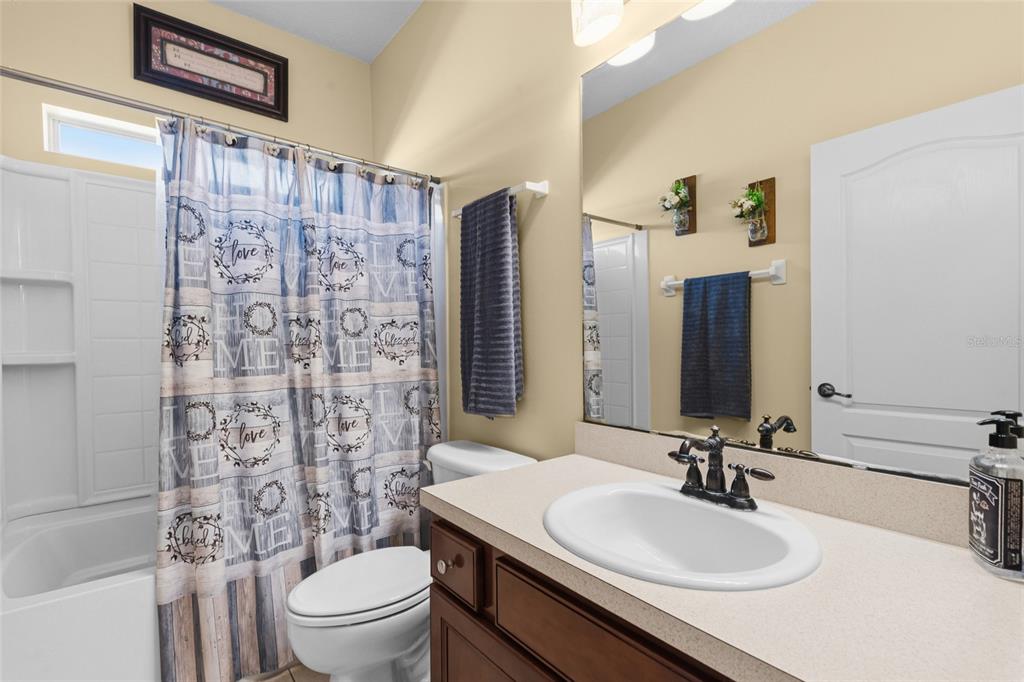 45095 Dutton Way Callahan, FL 32011 - Photo 29 of 36 a bathroom with a sink toilet a mirror and shower curtain