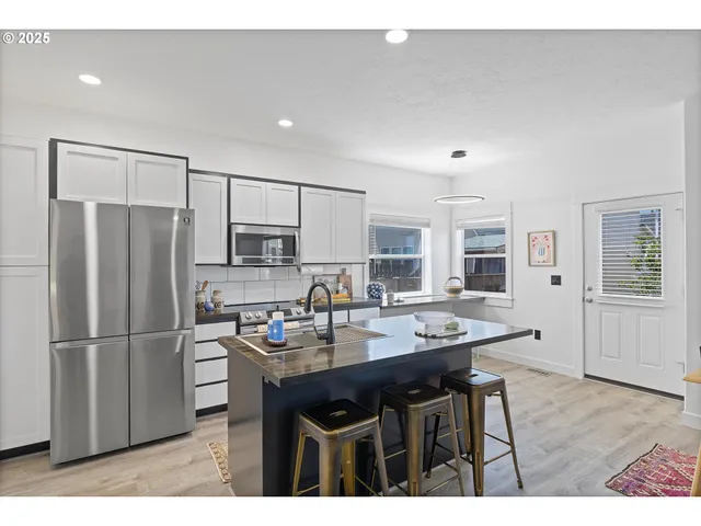 a kitchen with stainless steel appliances granite countertop a sink refrigerator and cabinets