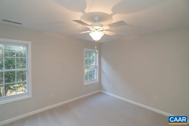 an empty room with windows and ceiling fan