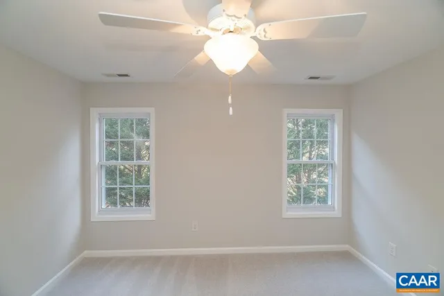 a view of an empty room and chandelier fan