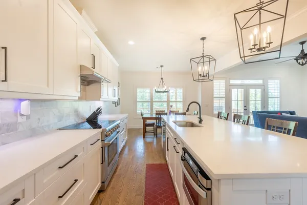 a large kitchen with stainless steel appliances granite countertop a sink a stove and a white cabinets